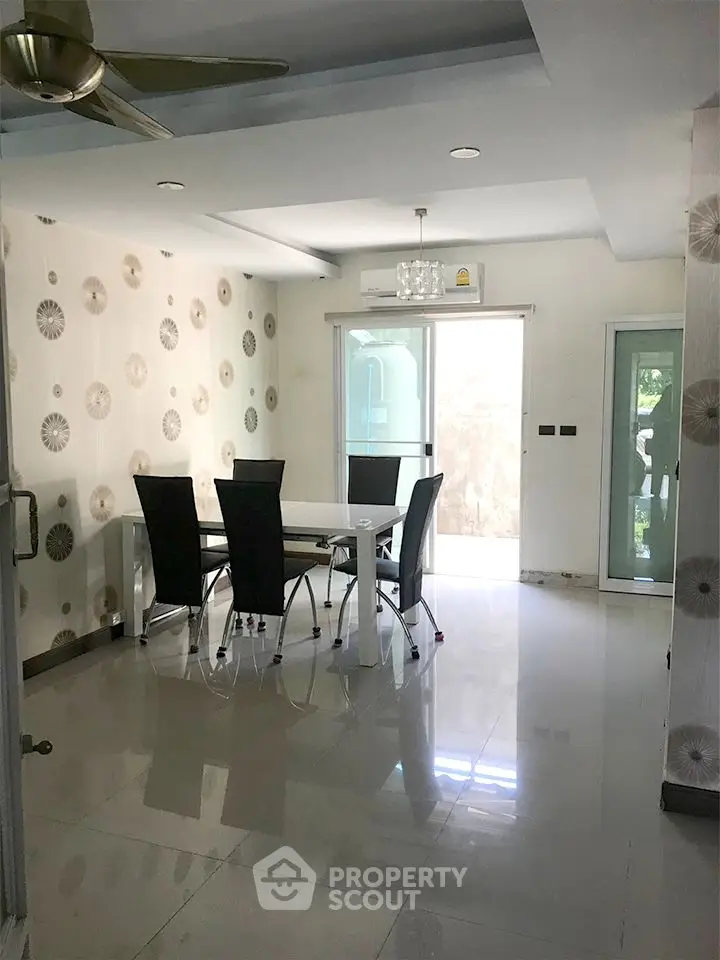 Modern dining area with stylish wallpaper and sleek furniture, featuring a ceiling fan and natural light.