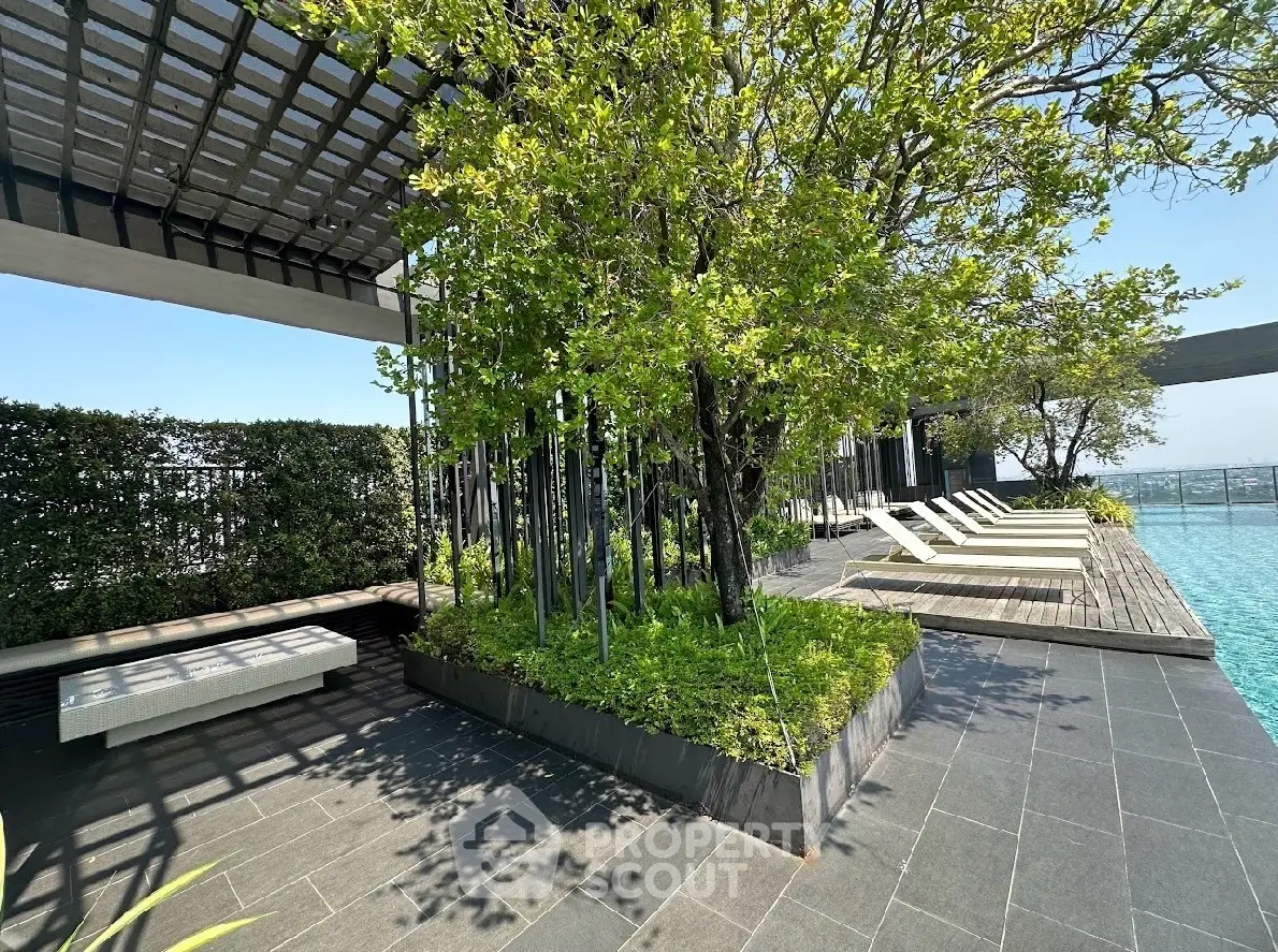 Luxurious rooftop pool area with sun loungers and lush greenery, offering a serene escape with stunning views.