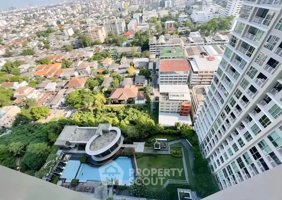 Stunning high-rise view of cityscape and modern residential building with pool and lush greenery.