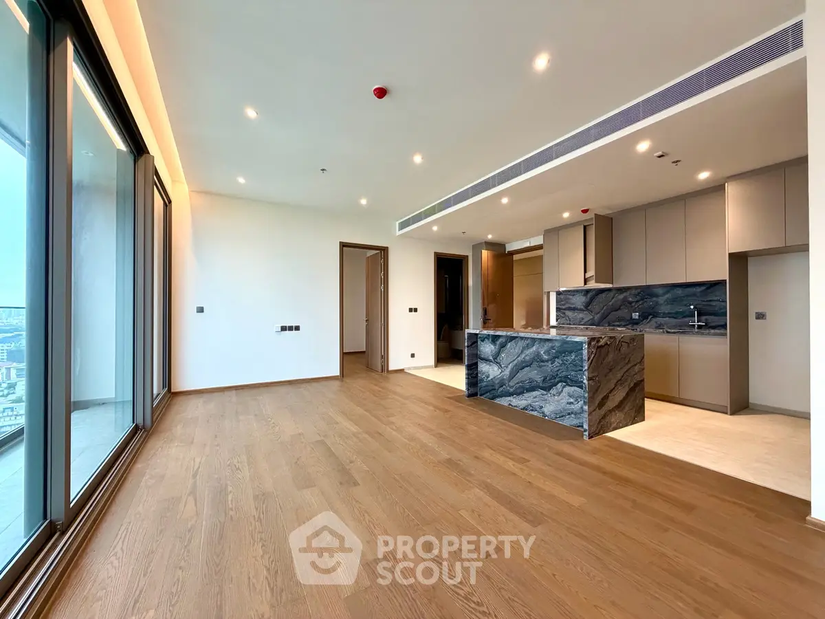 Spacious modern living room with open kitchen and stunning city view from large windows.