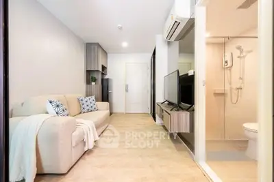 Modern living room with cozy sofa and TV, open view to bathroom, stylish interior design.