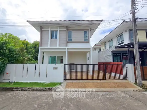 Modern two-story house with gated driveway and lush greenery