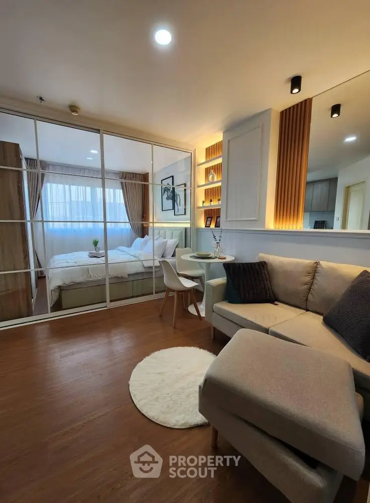 Modern studio apartment with cozy living area and stylish bedroom separated by glass partition.