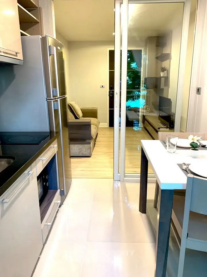 Modern apartment kitchen with sleek appliances and open view to cozy living room.