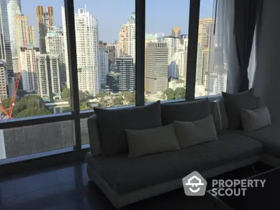 Spacious living room with floor-to-ceiling windows offering panoramic city views, modern sofa, and sleek design.