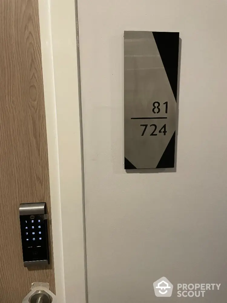 Modern apartment door with electronic lock and stylish room number plaque