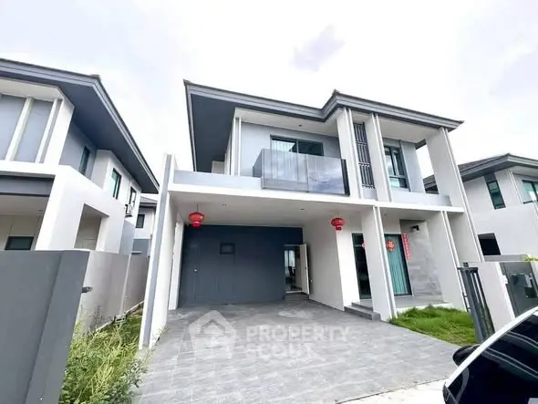 Modern two-story house with sleek design and spacious driveway in a suburban neighborhood.
