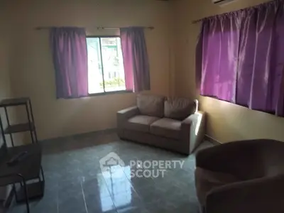 Cozy living room with natural light and purple curtains, perfect for relaxation.