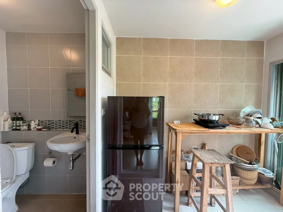 Compact kitchen with fridge and bathroom in modern apartment