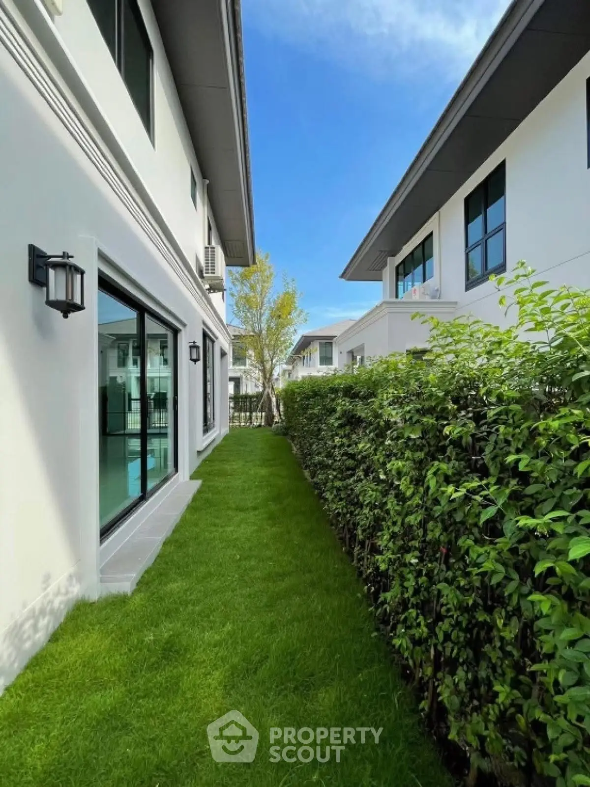 Modern residential buildings with lush green garden and clear blue sky.