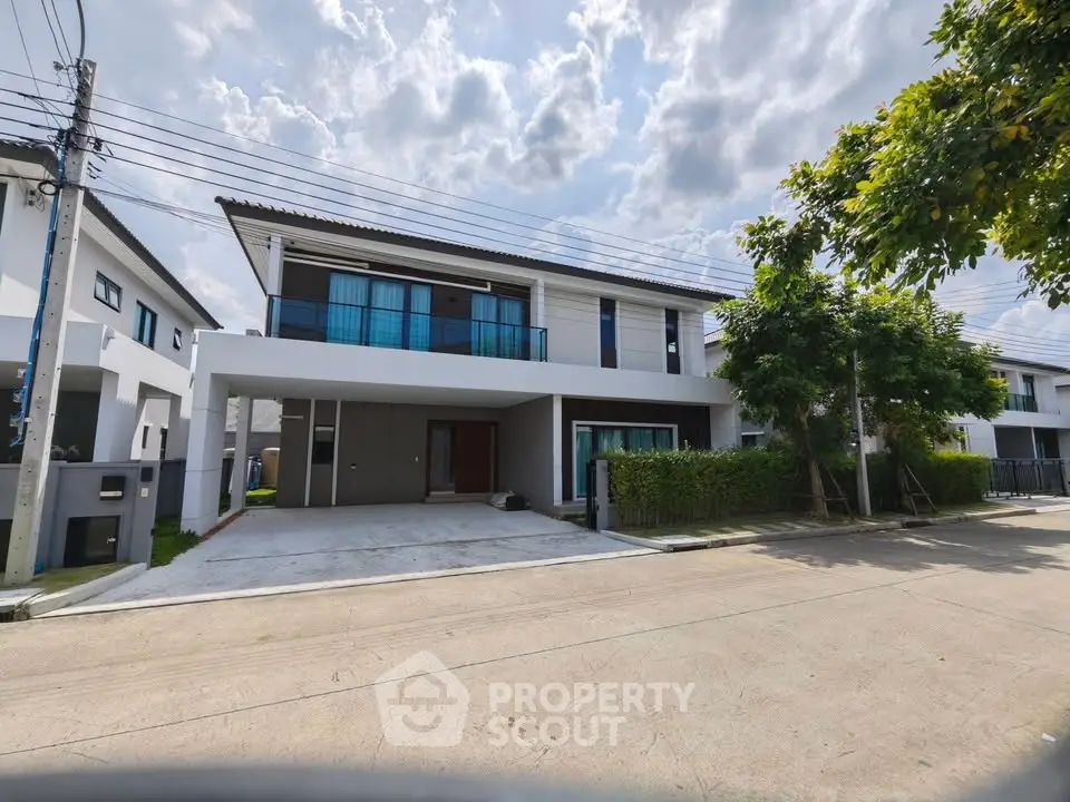 Modern two-story house with spacious driveway and lush greenery in a serene neighborhood.