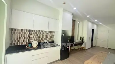 Modern kitchen with sleek cabinetry and integrated workspace in a stylish apartment.