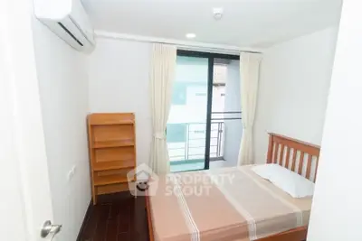 Cozy bedroom with balcony access, featuring a wooden bed frame and air conditioning, ideal for comfort seekers.