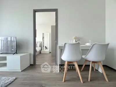 Modern minimalist living room with dining area and view into bedroom, featuring sleek furniture and neutral tones.