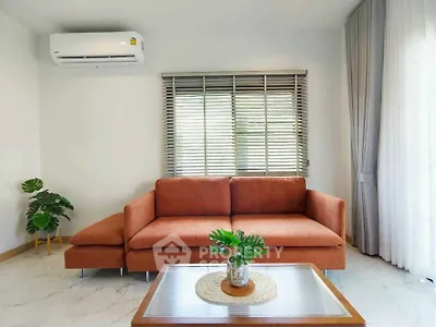 Modern living room with orange sofa, air conditioning, and stylish decor