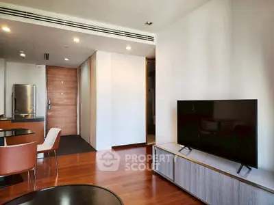 Modern living room with sleek TV and dining area, featuring wooden flooring and contemporary furniture.