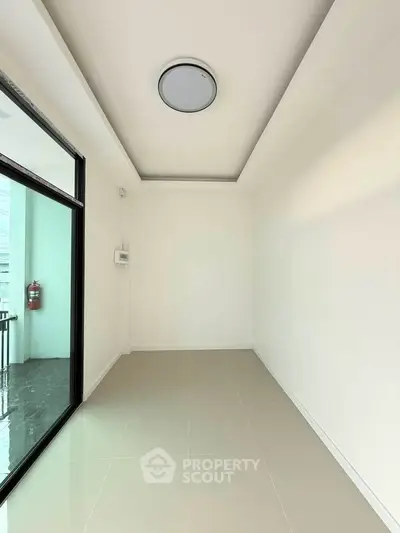 Spacious empty room with modern lighting and large window, perfect for customization.