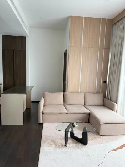 Modern living room with stylish beige sofa and glass coffee table, featuring elegant wood paneling.