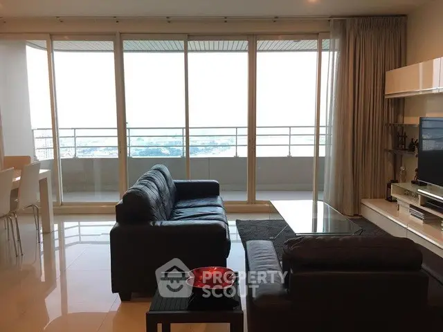 Spacious living room with modern furniture and large balcony offering stunning city views.