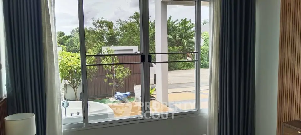 Modern home with large windows overlooking a lush garden and outdoor jacuzzi.