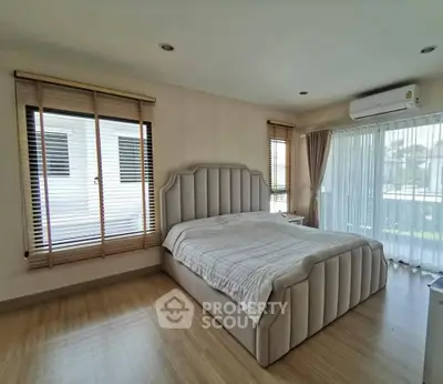 Spacious bedroom with elegant bed and large windows offering natural light.