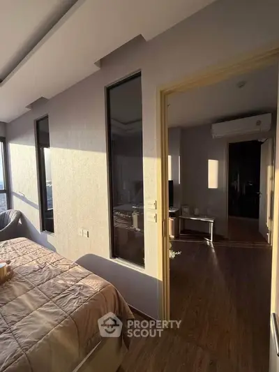 Sunlit modern bedroom with wooden flooring and large windows offering a serene ambiance.