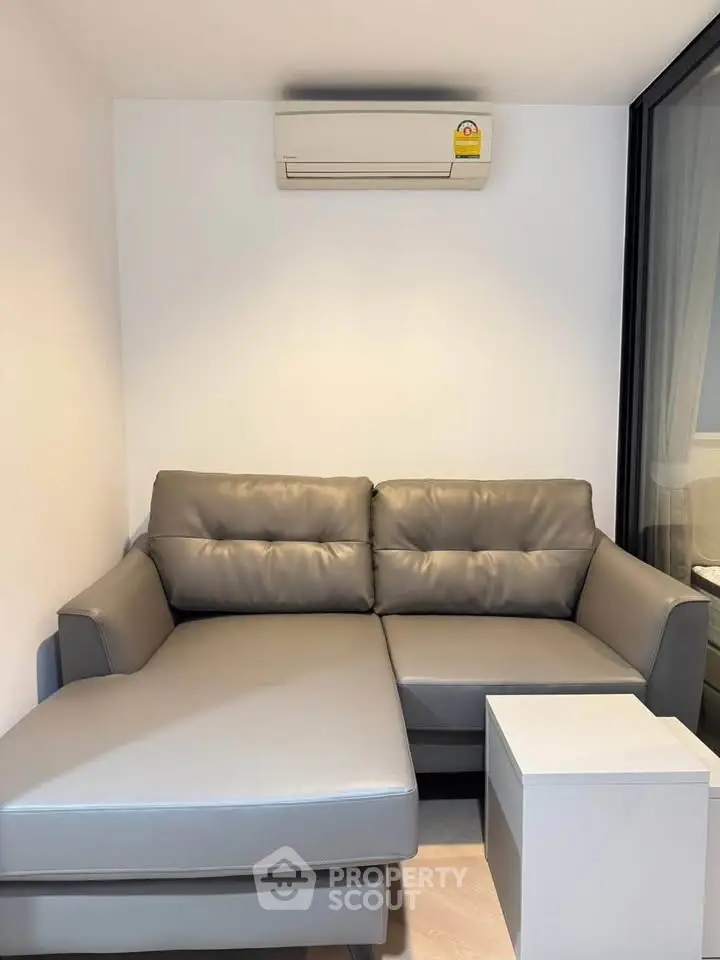 Modern living room with sleek gray sectional sofa and air conditioning unit.