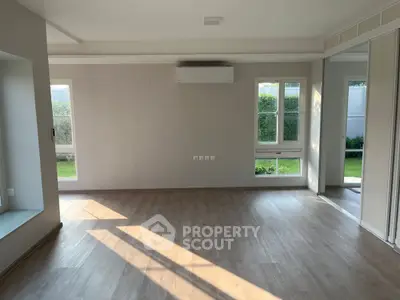 Spacious living room with large windows and garden view, perfect for natural light lovers.