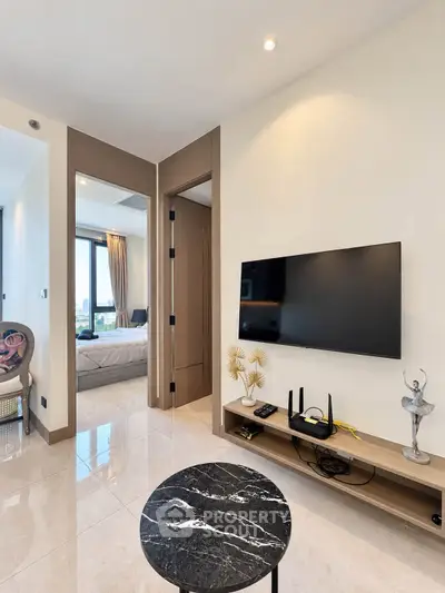 Modern living room with sleek TV setup and glimpse of cozy bedroom