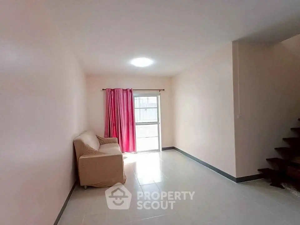 Spacious living room with natural light and cozy sofa, ideal for relaxation.