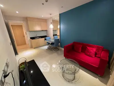 Modern living room with vibrant red sofa and sleek kitchen area