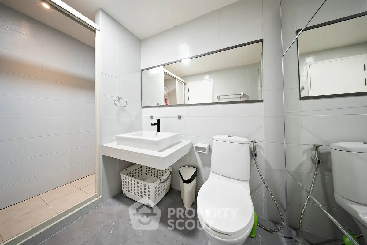 Modern bathroom with sleek fixtures and spacious design, featuring a large mirror and contemporary sink.