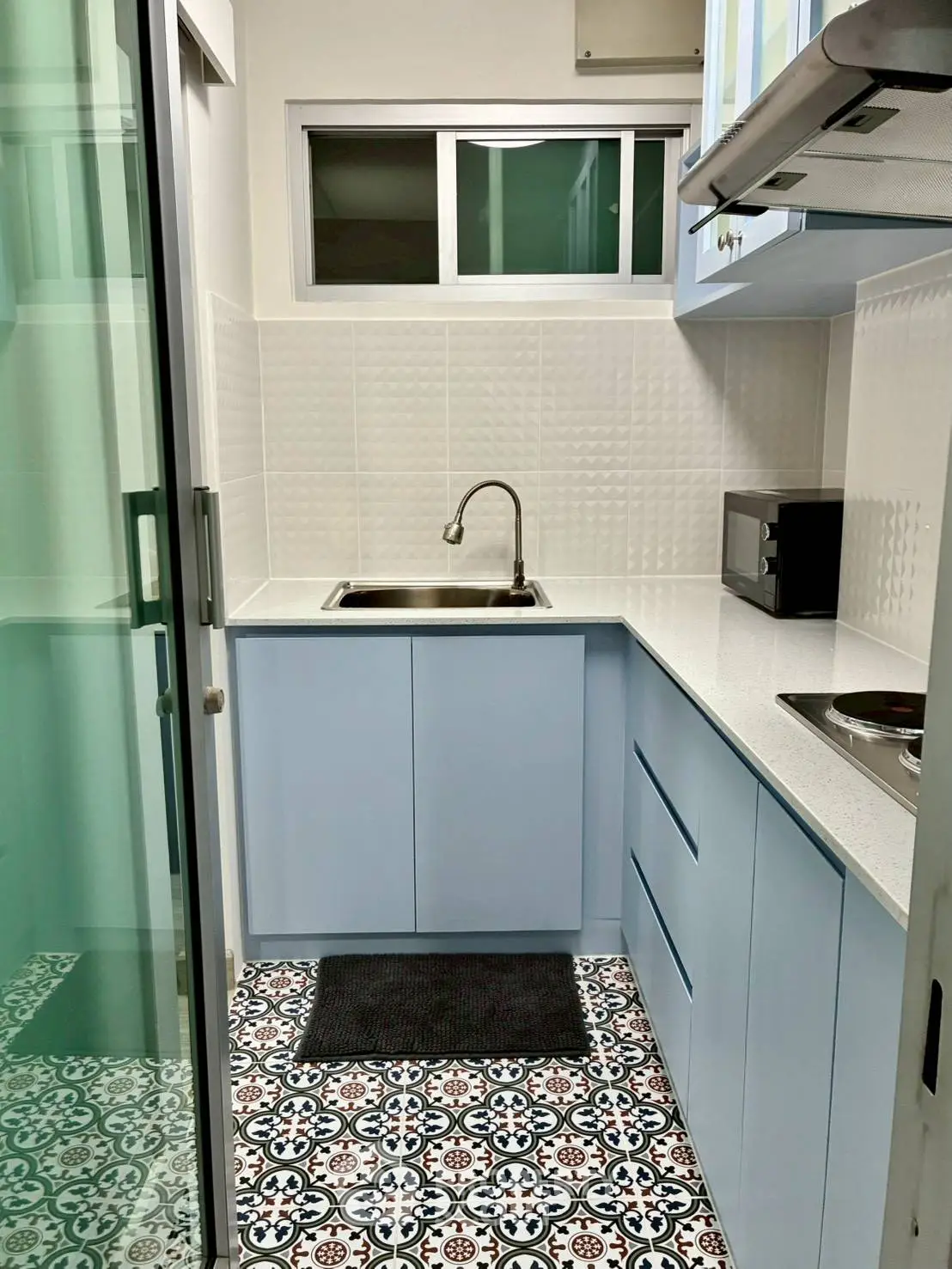 Charming compact kitchen with modern blue cabinetry and patterned tile flooring