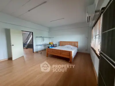 Spacious bedroom with wooden flooring and minimalist decor