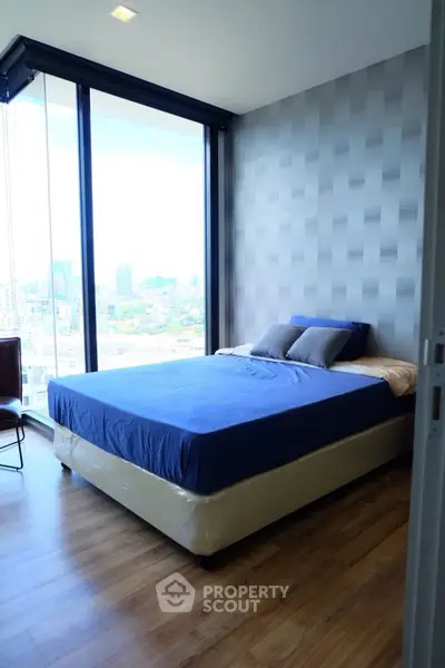 Modern bedroom with floor-to-ceiling windows offering stunning city views.