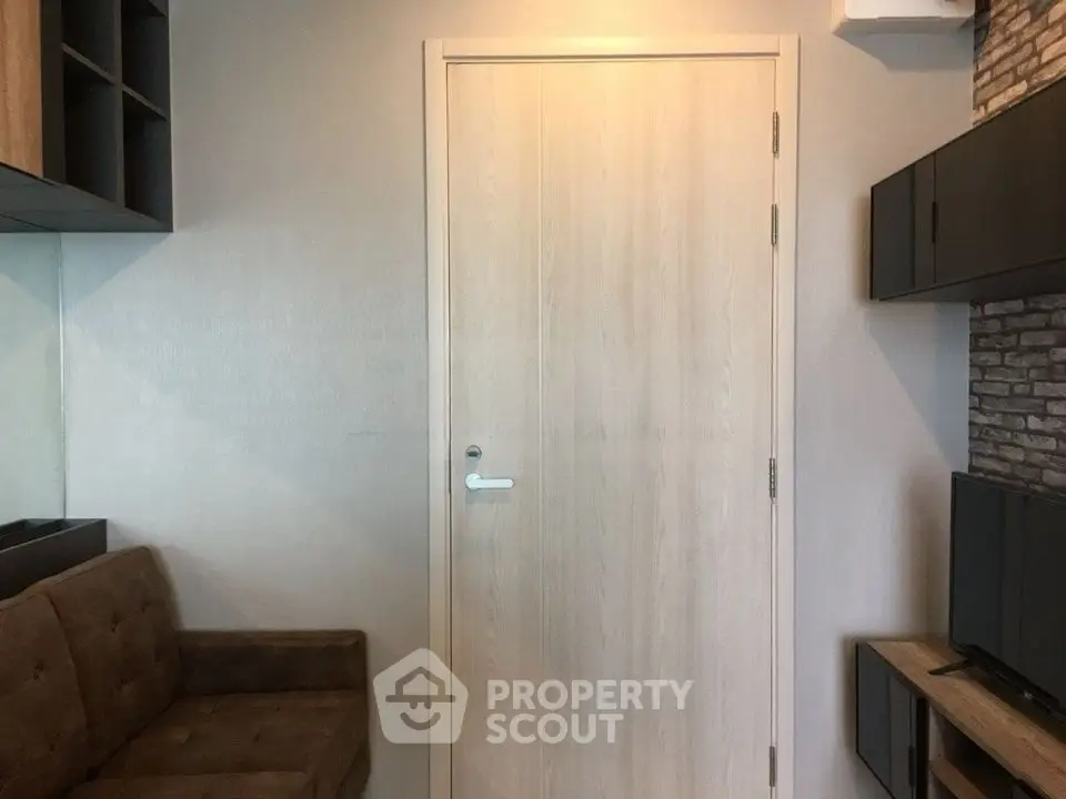 Modern living room with sleek furniture and neutral tones, featuring a stylish wooden door and built-in shelving.