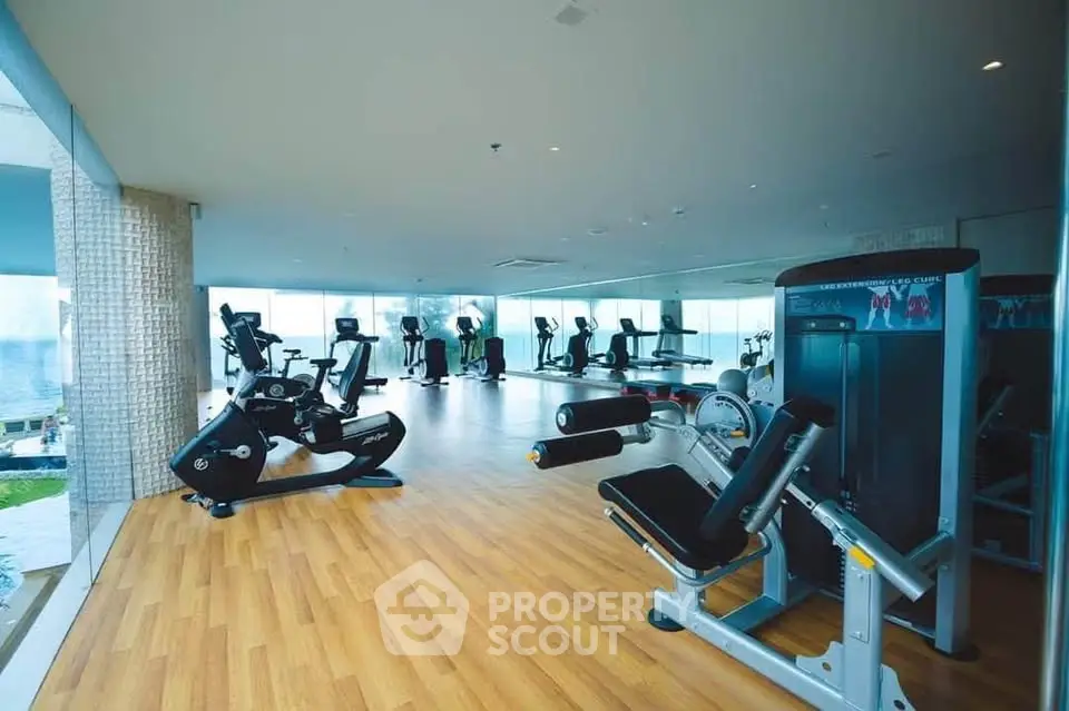 Spacious modern gym with state-of-the-art equipment and panoramic windows in luxury building.