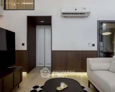 Modern living room with sleek design, featuring a wall-mounted air conditioner and stylish furniture.