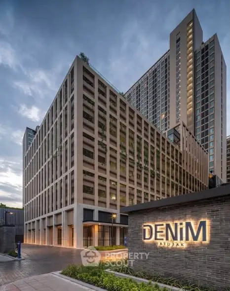 Modern high-rise building with sleek architecture and illuminated signage at dusk.