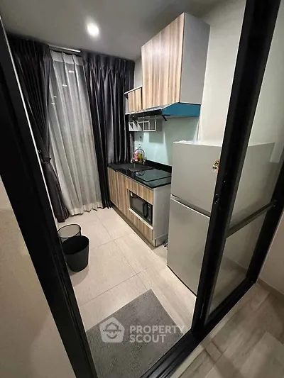 Modern compact kitchen with sleek appliances and stylish cabinetry in a cozy apartment setting.