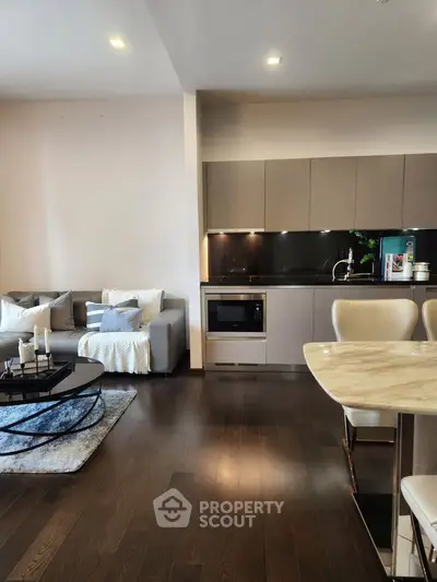 Modern open-plan living room with sleek kitchen and cozy seating area, perfect for entertaining.