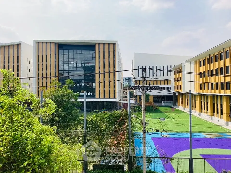 Modern educational campus with vibrant sports field and contemporary architecture.