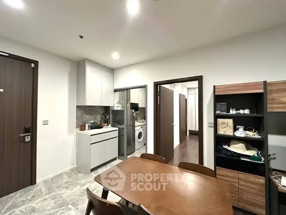 Modern kitchen with dining area, featuring sleek cabinetry and integrated appliances in a stylish apartment.