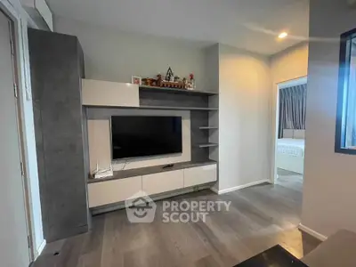 Modern living room with sleek TV unit and open doorway to bedroom, showcasing contemporary design.