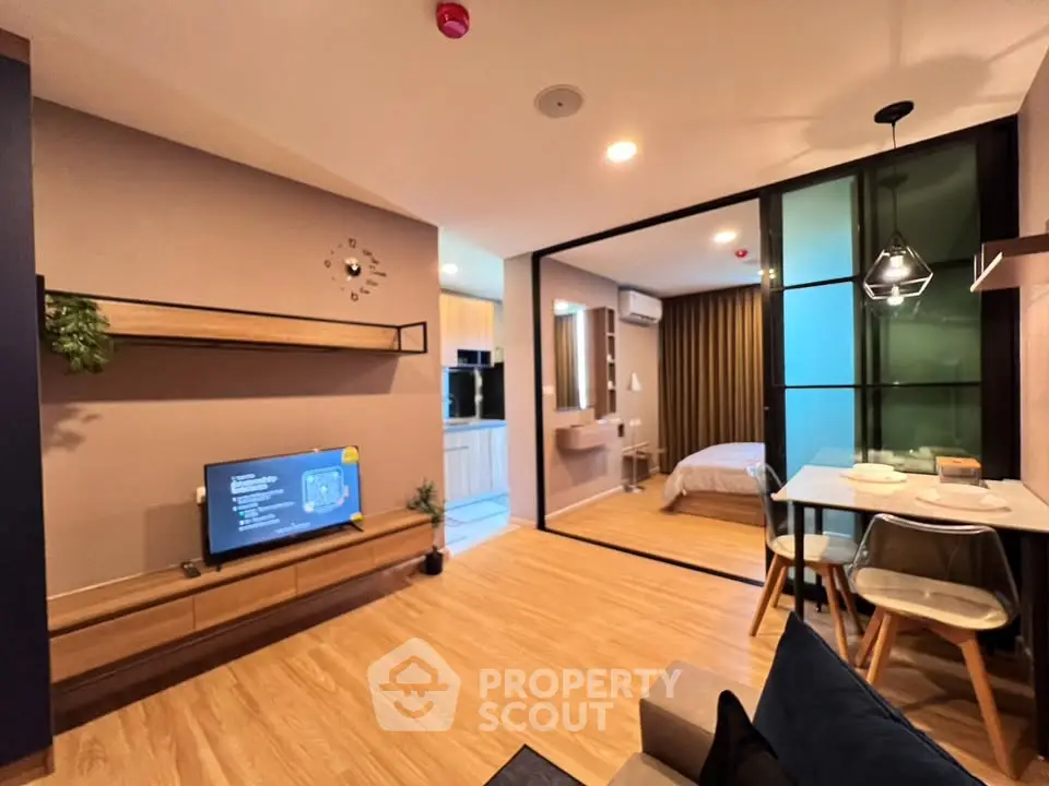 Modern open-plan living room with dining area and view into cozy bedroom