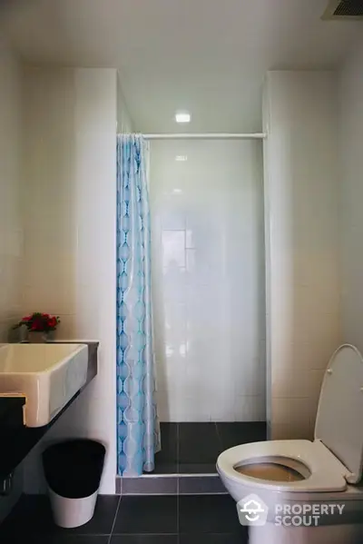 Pristine white bathroom with a modern shower, adorned with a stylish blue curtain, offering a serene and clean space for relaxation and rejuvenation.