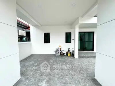Modern covered patio with sleek tile flooring and white walls, perfect for outdoor relaxation.