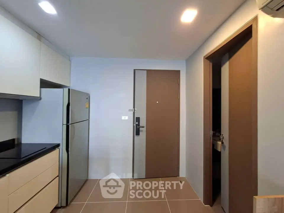 Modern kitchen with sleek cabinetry and stainless steel fridge in a compact apartment.