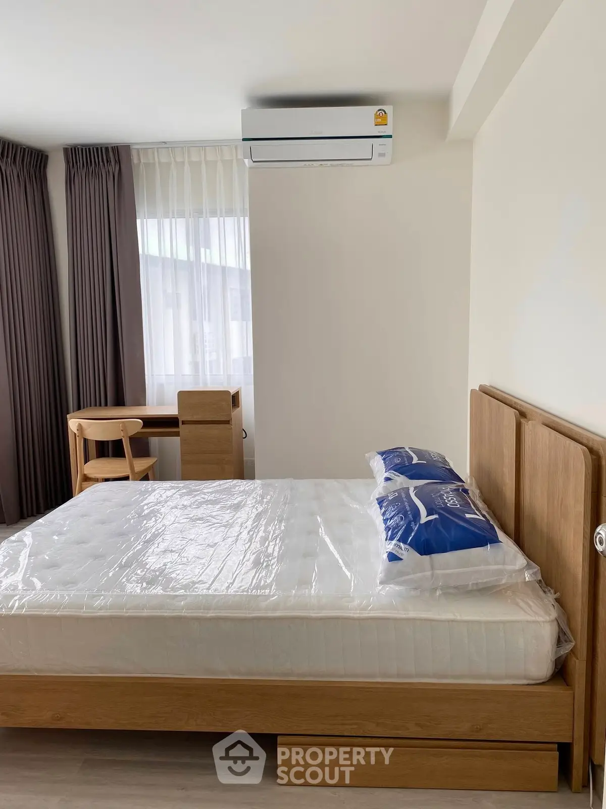Modern bedroom with wooden furniture and air conditioning, featuring a large window with curtains.