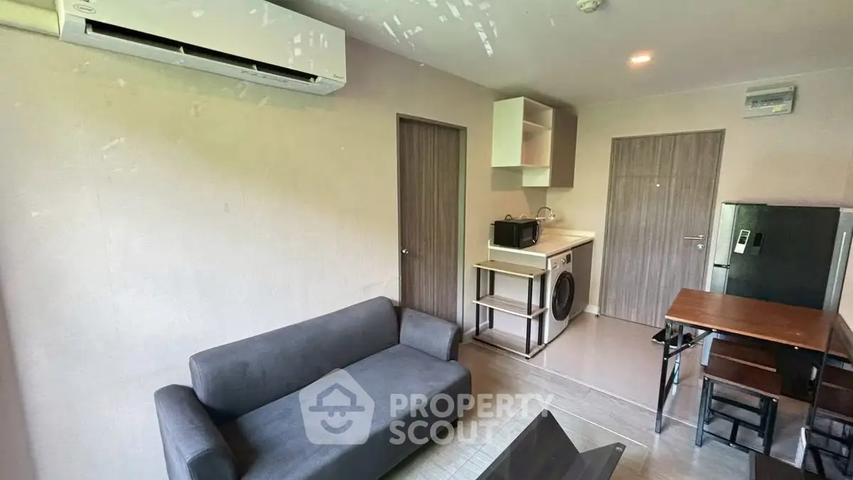 Modern living room with compact kitchen and washing machine, ideal for urban living.